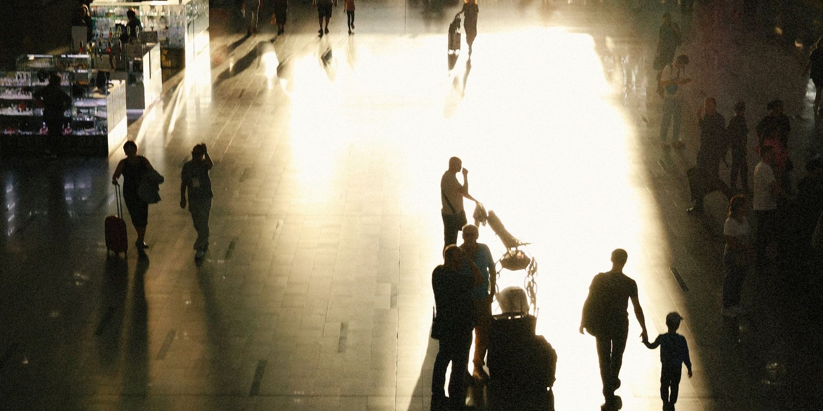 Travellers crossing an airport concourse in evening light