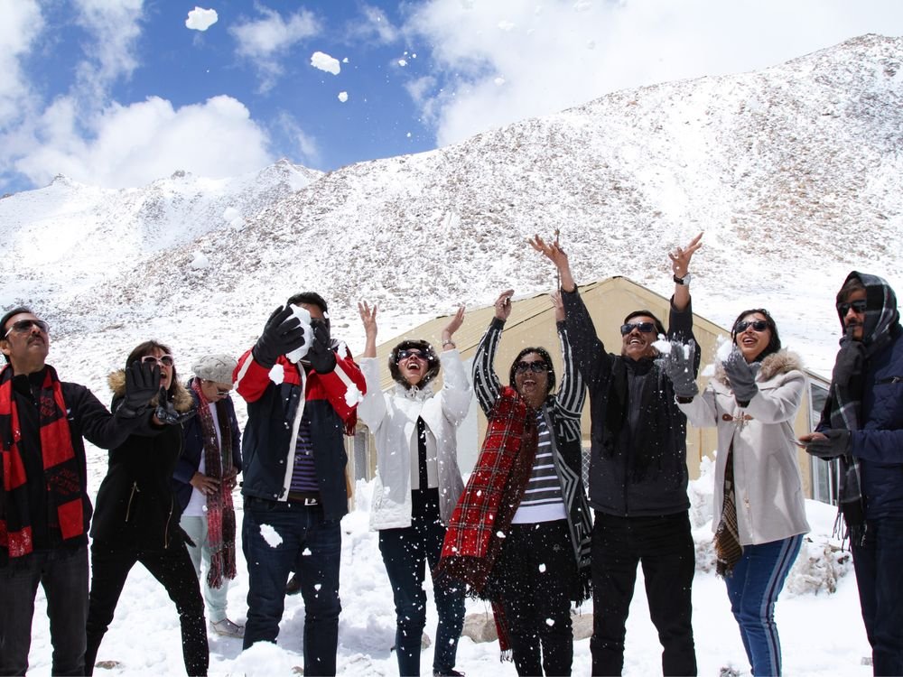 A group throwing snow into the air in the mountains