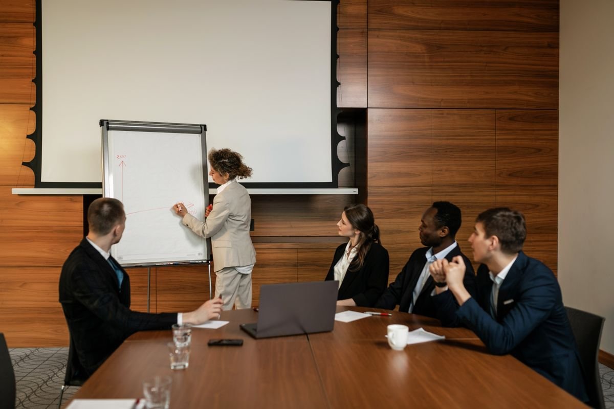 A small team around a meeting table while a colleague works at a flip chart